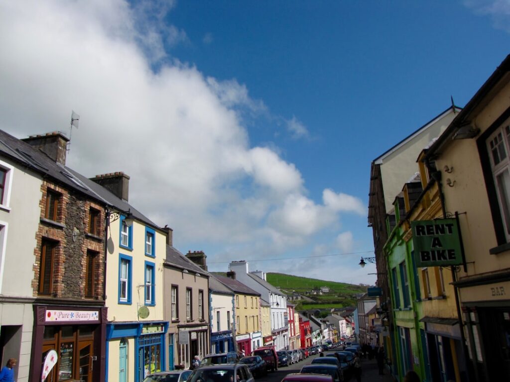 Colorful buildings line a street with green hills
