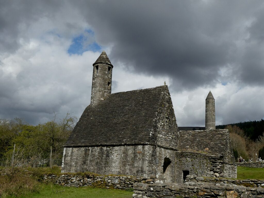 Ancient stone church with round towers under dramatic cloudy sky