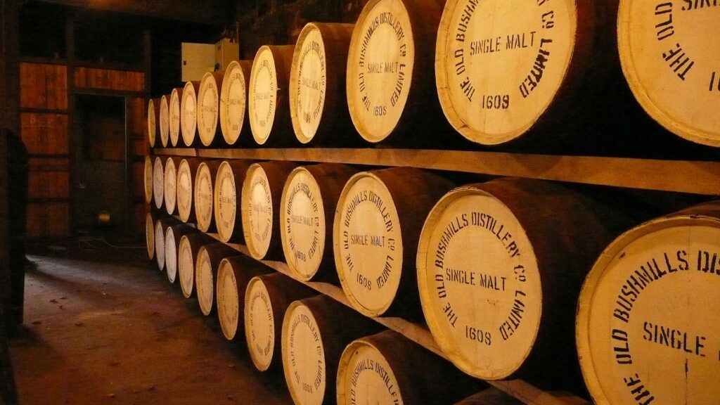 Wooden whiskey barrels stacked in rows inside a distillery warehouse