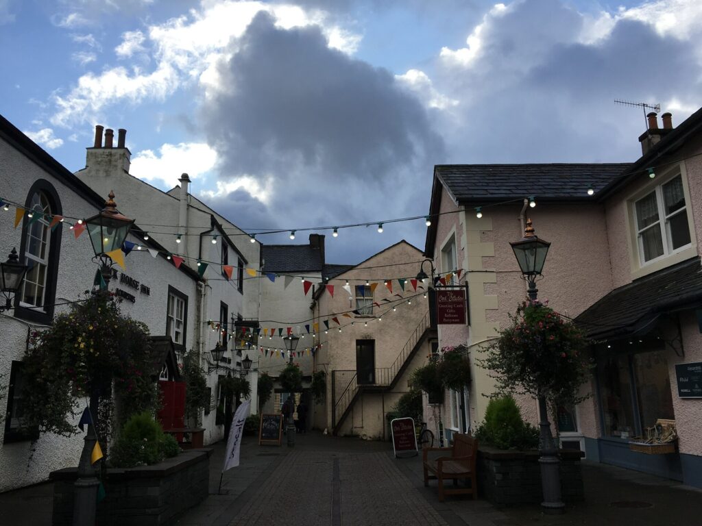 Charming Irish village courtyard with white and pink buildings, bunting, and cloudy sky