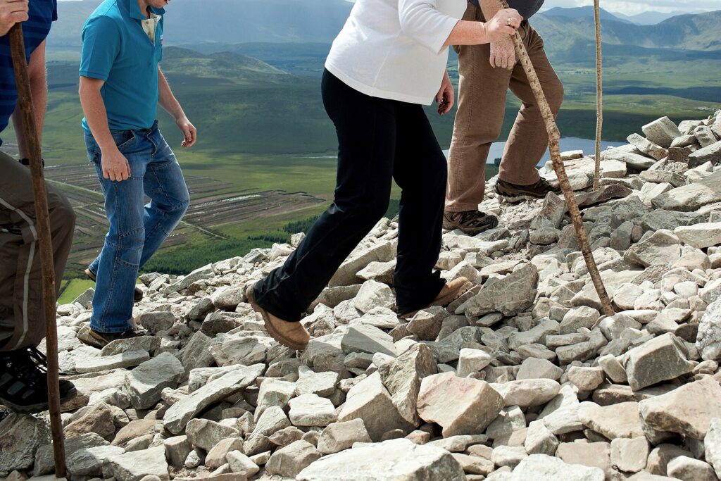 Group of hikers navigating rocky mountain terrain with valley landscape below