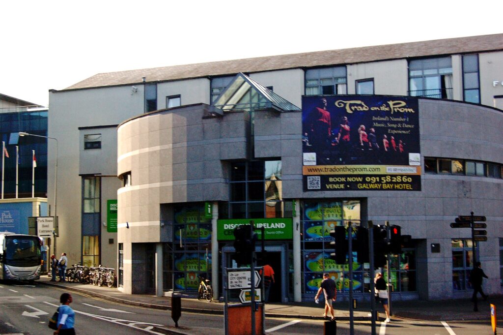 Modern curved building with green storefront and theatre advertisement on street corner