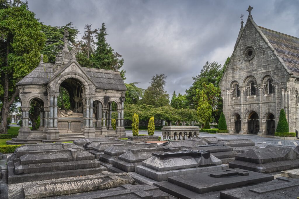 Stone chapel and ornate mausoleum in cemetery with gravestones
