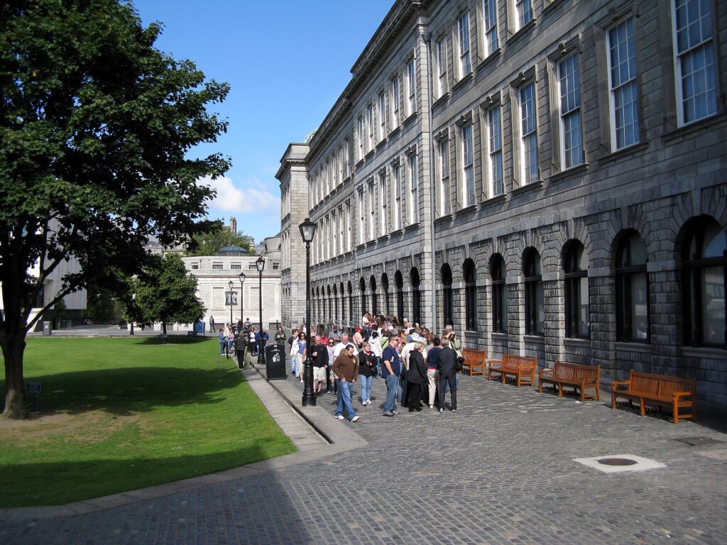 Group of tourists gathered outside a grand stone government building on a sunny day
