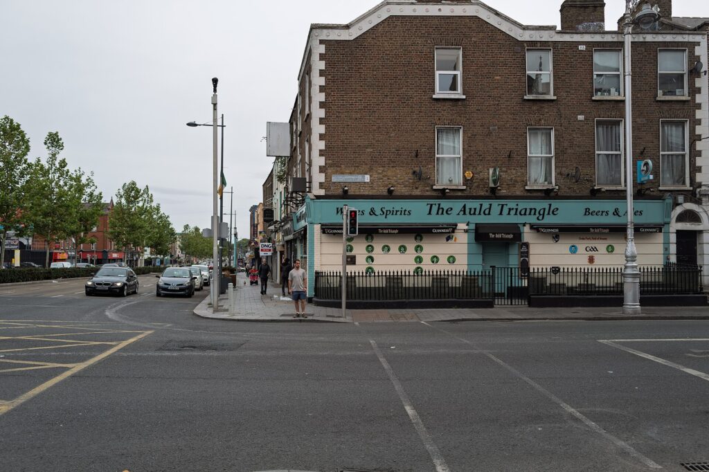 Street corner in Dublin showing The Auld Triangle pub with brick building and storefront