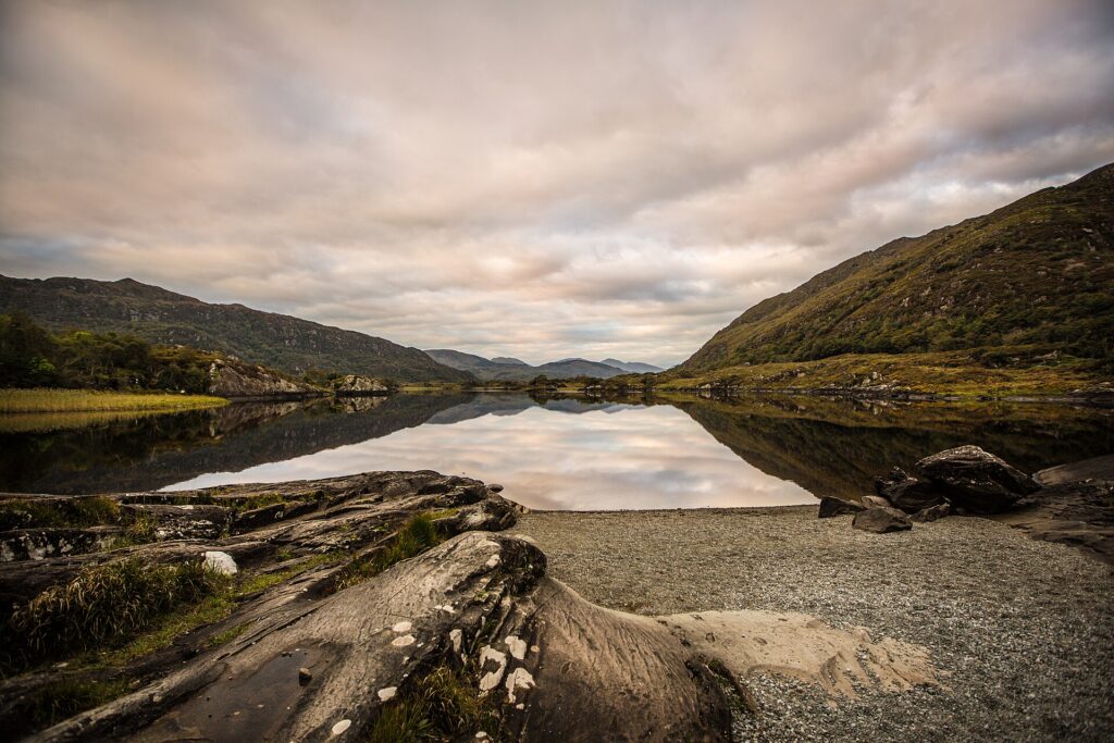 Still lake reflects cloudy sky between green mountains in valley