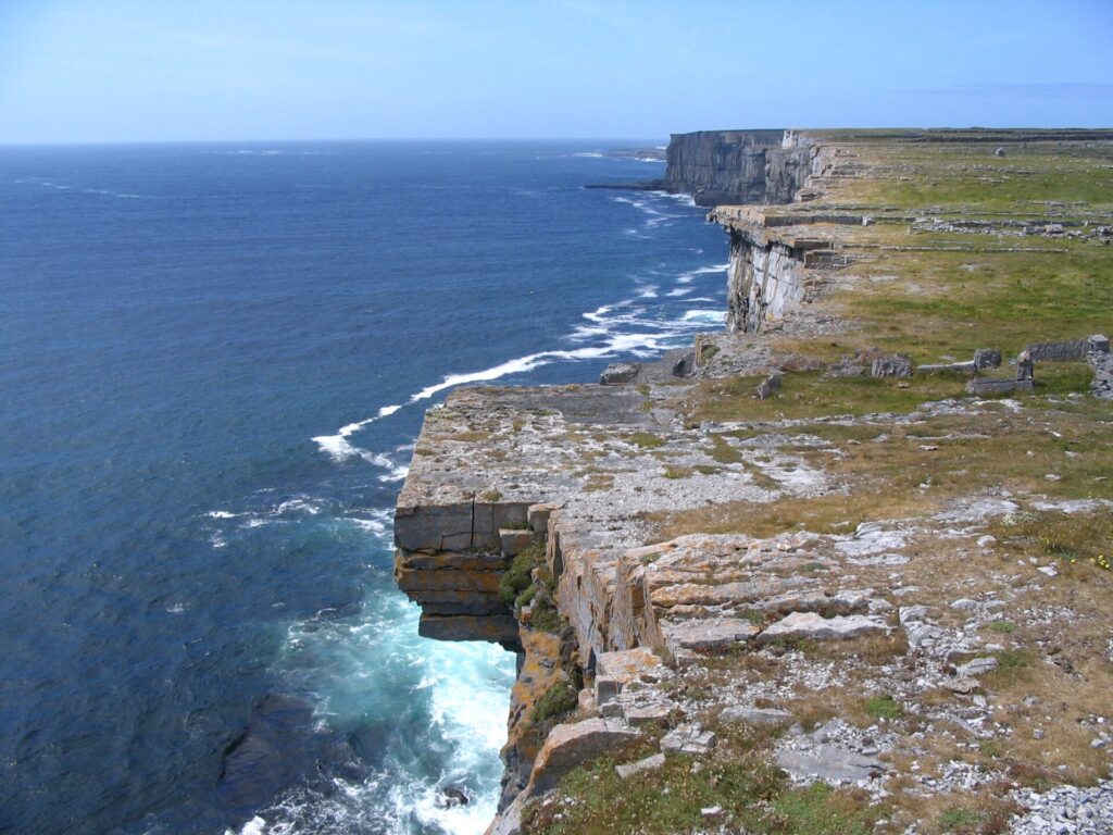 Dramatic coastal cliffs drop steeply to turbulent blue ocean waters below