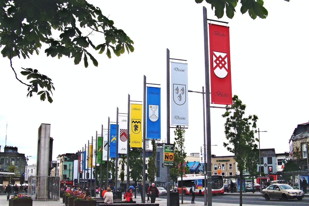 Colorful banners hanging from poles in a pedestrian street plaza