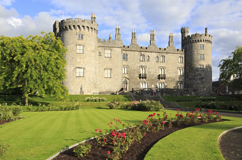 Medieval stone castle with towers and manicured gardens in summer sunlight