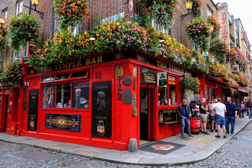 Bright red corner pub decorated with hanging flower baskets and ivy