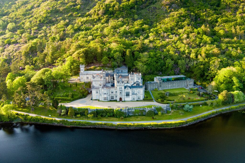 Aerial view of white castle on peninsula surrounded by forest and water