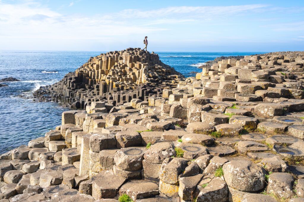 Person standing atop hexagonal basalt columns overlooking the sea