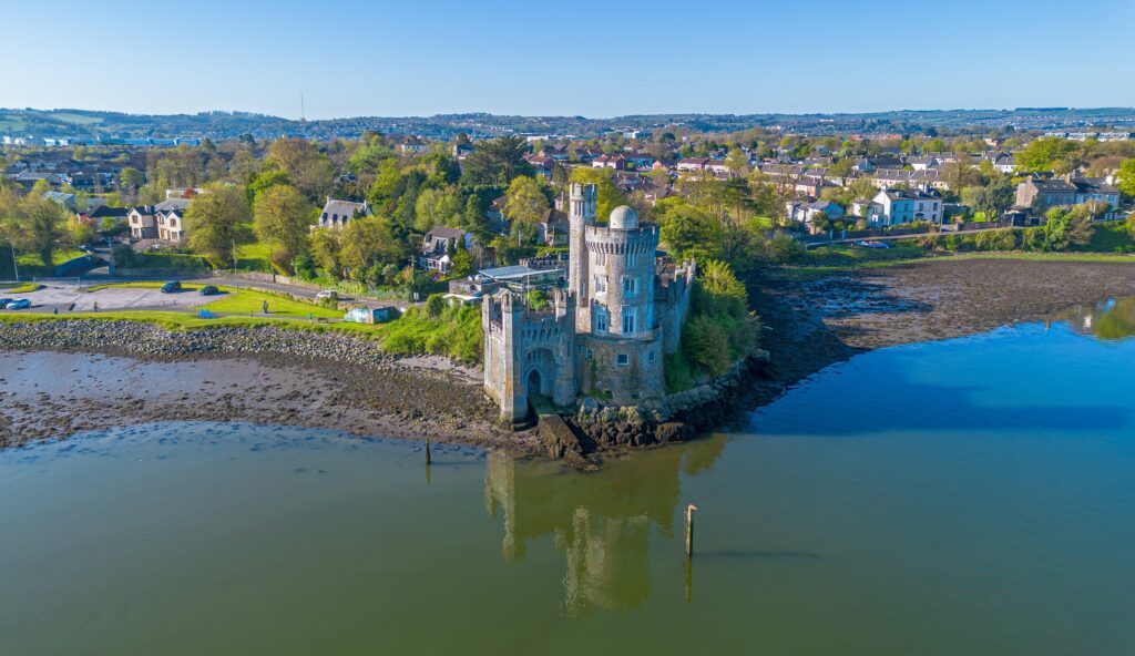 Medieval castle on rocky island surrounded by water with coastal town beyond