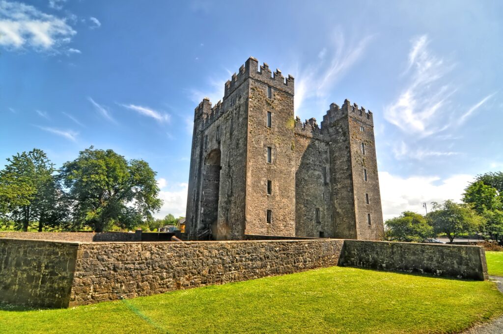 Medieval stone castle with crenellated towers surrounded by grassy grounds and defensive walls