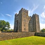 Medieval stone castle with crenellated towers surrounded by grassy grounds and defensive walls