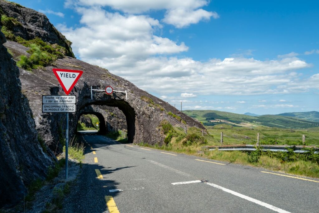 Scenic mountain road with a stone tunnel and yield sign