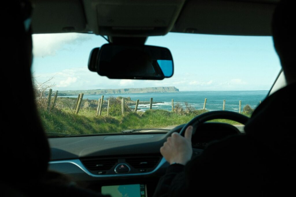 A man driving a car down a road next to the ocean